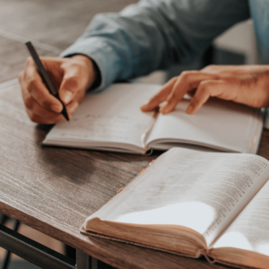 Une personne rédige un texte pour illustrer les 5 commandements du manuel opératoire franchise, la Bible du franchisé