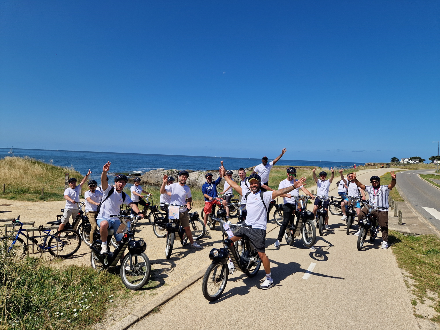 Equipe de la franchise Ecolave posant sur des vélos en bord de mer
